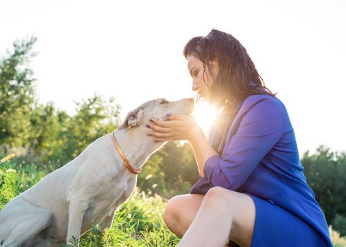 Pet care. Pet adoption. Young woman hugging her mixed breed dog in the park in the sunset