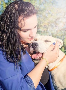 Pet care. Pet adoption. Young woman playing and hugging her dog in the park