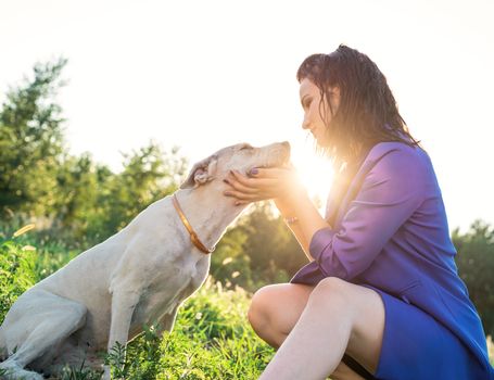 Pet care. Pet adoption. Young woman hugging her mixed breed dog in the park in the sunset