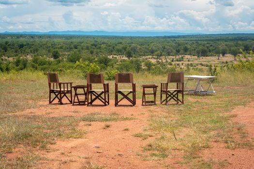 Empty chairs and table with view on the landscape of an African national park during a safari trip. Travel and tourism.