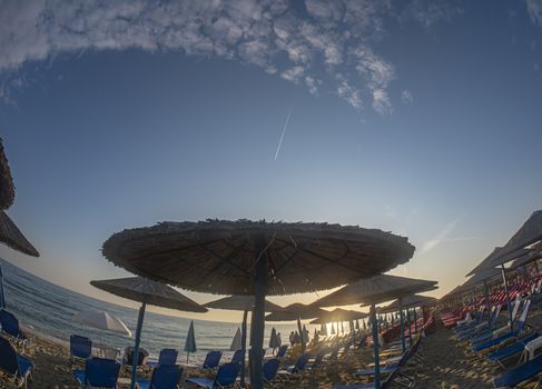 sunset beach with umbrellas and sunbeds without tourists