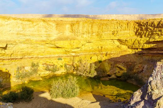 View of a water hole and layered rock formation, along the Ramon Colors Route, in Makhtesh Ramon (Ramon Crater), the Negev desert, southern Israel
