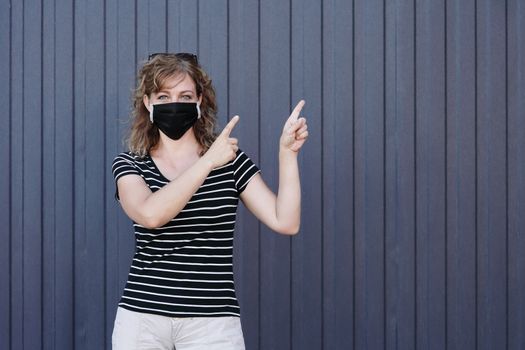 Portrait of a Girl in a protective mask, free space for text. Social distancing. Blue striped wall in the background