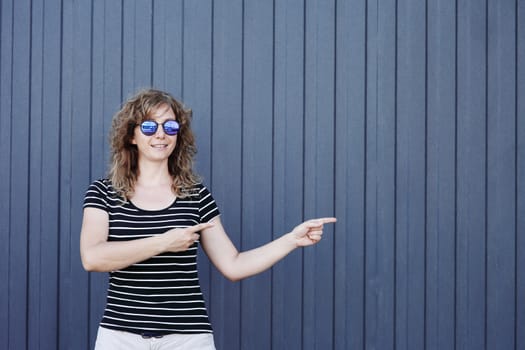 Woman portrait in sunglasses, free space for text. Blue striped wall in the background