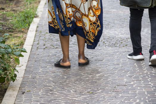 legs of African woman with slippers on her feet while walking
