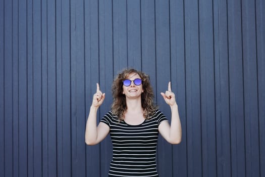 Woman portrait in sunglasses, free space for text. Blue striped wall in the background