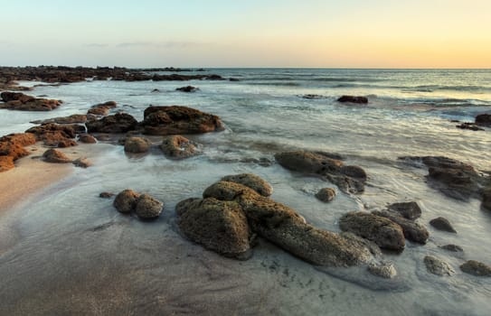 Rocky beach uncovered in low tide after evening sunset.