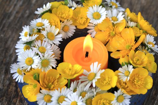Summer flower decoration with daisies, buttercups and a candle