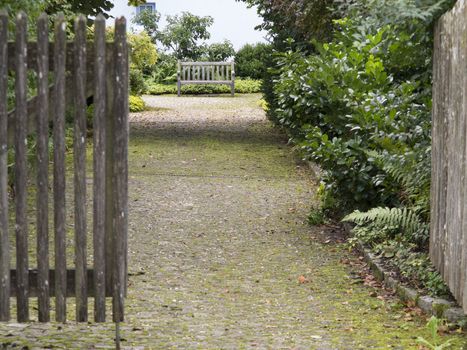 Open gate and entranceway leading to a wooden bench