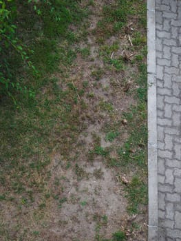 top view of tiled pedestrian pavement sidewalk by a meadow