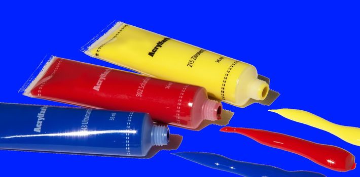 Yellow, red, blue akrill paint tubes with blue background.High quality photo