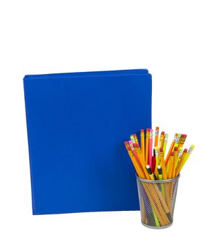 Blue notebook with lots of copy space and colorful pencils in a pencil holder. Isolated on white. 