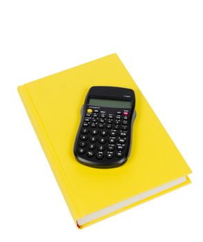 Vertical shot of a bright yellow colored book with a calculator on top isolated on a white background.