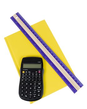 Close up shot of a brightly yellow colored school book with a calculator and purple ruler resting on top. Isolated on white background. 