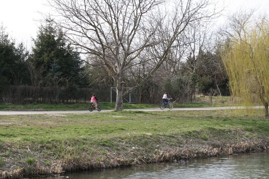 Afternoon still life in Újszeged. Children riding the bike at the Maros coast. High quality photo