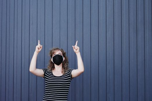 Portrait of a Girl in a protective mask, free space for text. Social distancing. Blue striped wall in the background