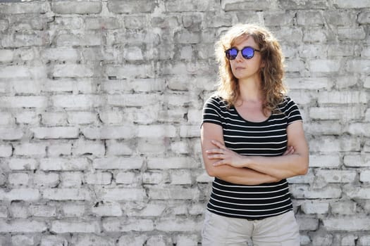 Woman portrait in sunglasses, free space for text. White brick wall in the background