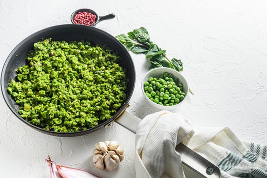 Homemade mushy peas cooked frying pan and peas in bowl with mint shallot pepper and salt over white stone surface organic keto food overhead photo side view space for text.