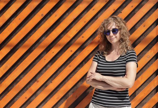 Woman portrait in sunglasses, free space for text. Orange wooden wall in the background
