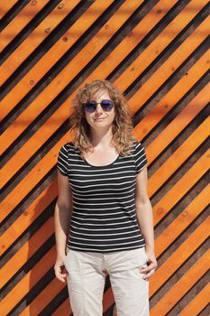 Woman portrait in sunglasses, free space for text. Orange wooden wall in the background