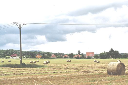 Straw bales on the outskirts of Miskolc in the great field with houses and overturned skies. High quality photo