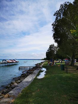 A group of people standing next to a body of water. High quality photo