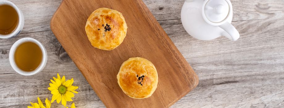 Moon cake yolk pastry, mooncake for Mid-Autumn Festival holiday, top view design concept on bright wooden table with copy space, flat lay, overhead shot