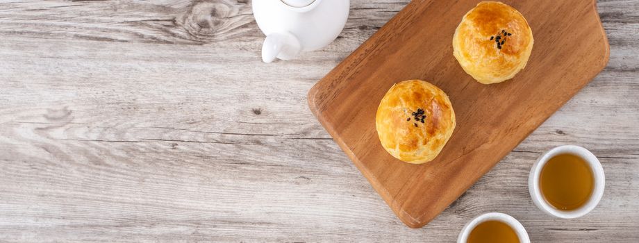 Moon cake yolk pastry, mooncake for Mid-Autumn Festival holiday, top view design concept on bright wooden table with copy space, flat lay, overhead shot