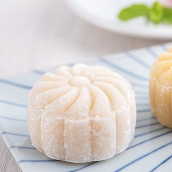 Colorful snow skin moon cake, sweet snowy mooncake, traditional savory dessert for Mid-Autumn Festival on bright wooden background, close up, lifestyle.