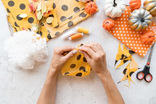 Step by step instruction of making halloween textile DIY pumpkin craft. Step 3 - sewing a circle around and tie it up . Top view flat lay