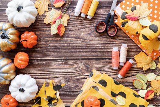 Halloween concept. Top view of Halloween decorations and sewing items making textile pumpkin craft with copy space over wooden background