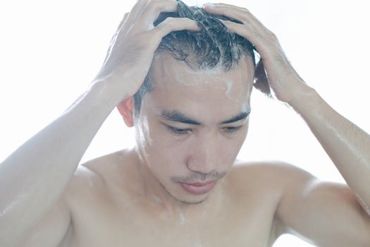 Closeup young man washing hair with with shampoo in the bathroom, vintage tone, selective focus