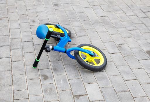 blue children bicycle lying on the sidewalk on summer day