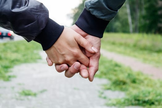 woman with a man holding a hand outdoor on summer day. hands closeup