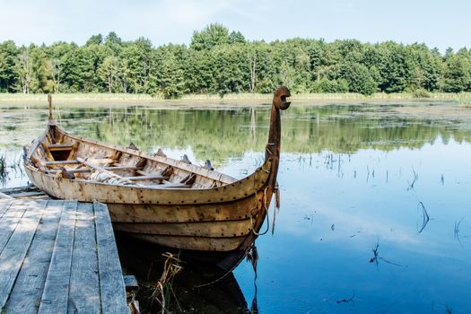 old wooden viking boat by the lake on sunny summer day