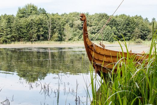 old wooden viking boat by the lake on sunny summer day