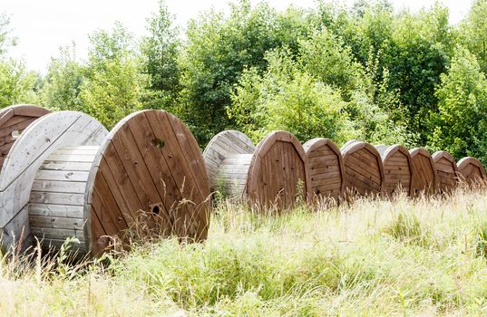 several large wooden spools in the forest on sunny summer day