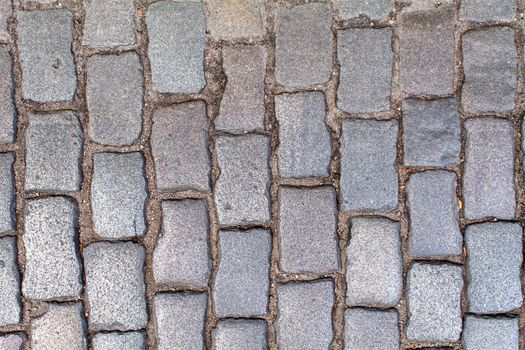 pavement of granite stone.old cobblestone road pavement texture, grass between stones. absrtact background. outdoor closeup