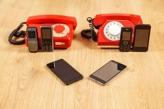 set of various old phones and modern smartphones on yellow wooden background. conceptual photo