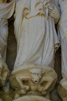 Fourteenth century  marble sculpture of a monkey at the feet of a Catholic apostle at Sé Cathedral, Évora, Portugal