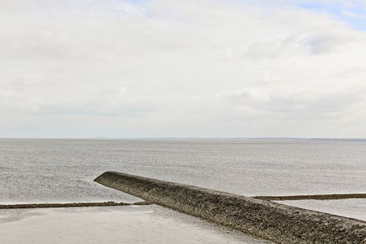 Water, clouds, dike and shells on the north German coast of Butjardingen in Lower Saxony, Germany.