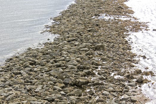 Water, stones, dike and rocks on the north German coast of Butjardingen in Lower Saxony, Germany.