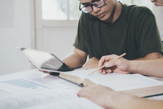 Learning, education and school concept. Young woman and man studying for a test or an exam. Tutor books with friends. Young students campus helps friend catching up and learning.