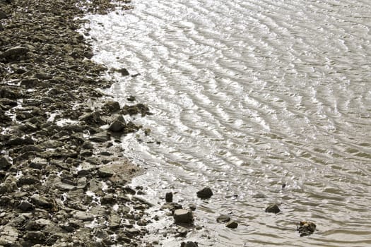 Water, stones, dike and rocks on the north German coast of Butjardingen in Lower Saxony, Germany.