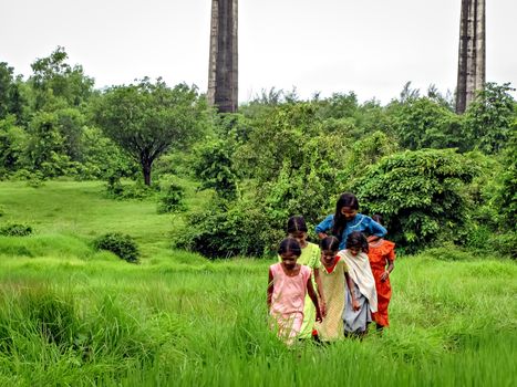 Khershet,Maharashtra,India-August 30th,2009:Village girls happily walking a small pathway surrounded by lush green fields after a drizzle in monsoon.