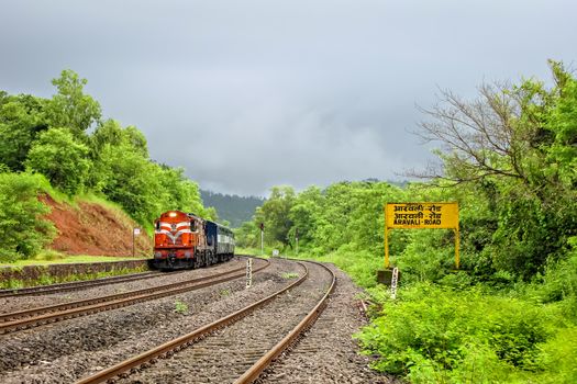 Aravali Road,Maharashtra,India-August 30th, 2009:Indian Railway's passenger carrying train entering a beautiful, scenic , small Aravali Road station, surrounded by lush green environment.