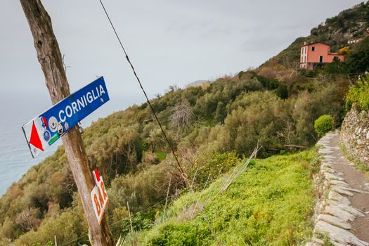 Signpost on the famous walking path linking the five towns, pointing to the town of Corniglia in the Cinque Terre, Italy