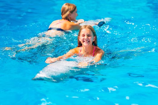 Happy little girl swimming with dolphins in Dolphinarium. Swimming, bathing and communication with dolphins.