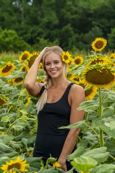 A gorgeous blonde model poses outdoors in a field of sunflowers while enjoying a summers day