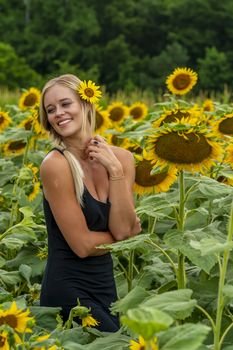 A gorgeous blonde model poses outdoors in a field of sunflowers while enjoying a summers day